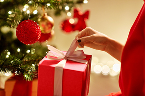 winter holidays, celebration and people concept - close up of woman with gift box at christmas tree at home