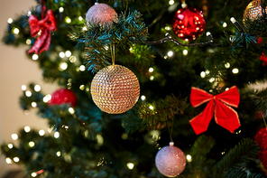 holidays, new year and celebration concept - golden christmas ball decoration hanging on artificial fir tree