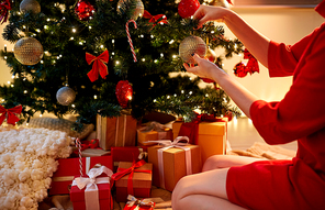 holidays, celebration and people concept - woman hands decorating christmas tree with ball