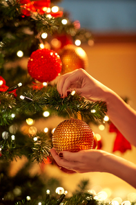 holidays, celebration and people concept - woman hands decorating christmas tree with ball