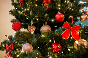 holidays, new year and celebration concept - green artificial christmas tree decorated with toys at home