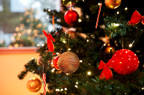 holidays, new year and celebration concept - green artificial christmas tree decorated with toys at home