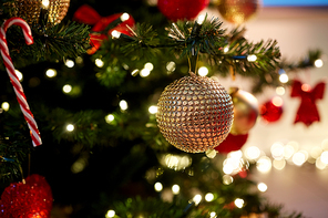 holidays, new year and celebration concept - golden christmas ball decoration hanging on artificial fir tree
