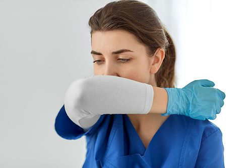 medicine, healthcare and people concept - doctor or nurse in gloves coughing covering mouth with her elbow