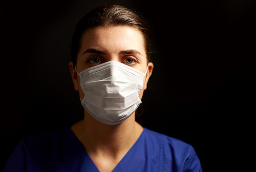 health, medicine and pandemic concept - young female doctor or nurse wearing face protective mask for protection from virus disease over black background