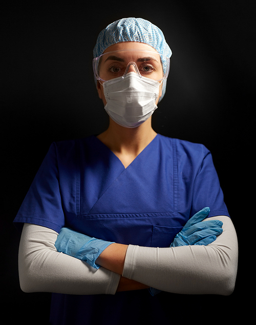 health, medicine and pandemic concept - young female doctor or nurse wearing goggles, hat, gloves and face protective mask for protection from virus disease over black background