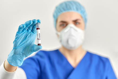 medicine, health and pandemic concept - close up of young female doctor or nurse holding beaker with coronavirus blood test