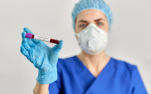 medicine, health and pandemic concept - close up of young female doctor or nurse holding beaker with coronavirus blood test