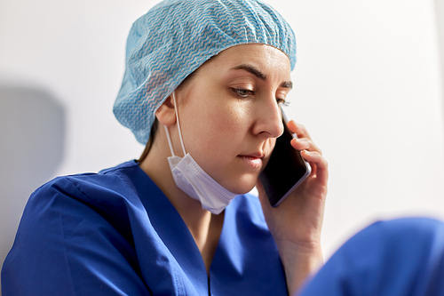 medicine, healthcare and pandemic concept - close up of sad young female doctor or nurse sitting on floor and calling on smartphone