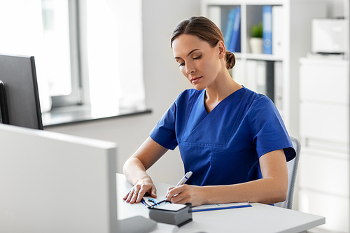 medicine, technology and healthcare concept - female doctor or nurse with clipboard working at hospital