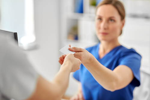 medicine, people and healthcare concept - close up of patient giving tag to doctor or nurse at hospital