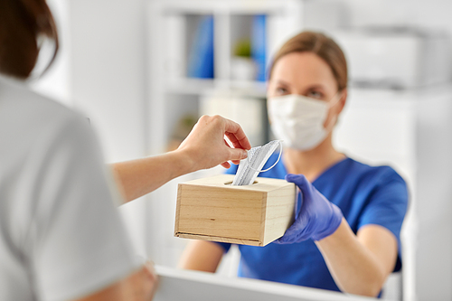 medicine, pandemic and healthcare concept - close up of female doctor or nurse offering mask to patient at hospital