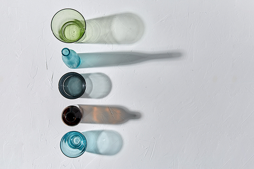 glassware concept - different glasses and bottles dropping shadows on white surface