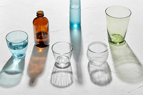 glassware concept - different glasses and bottles dropping shadows on white surface