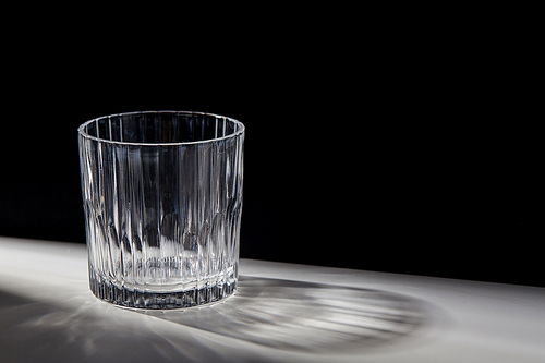 drink and glassware concept - empty faceted glass on table over black background