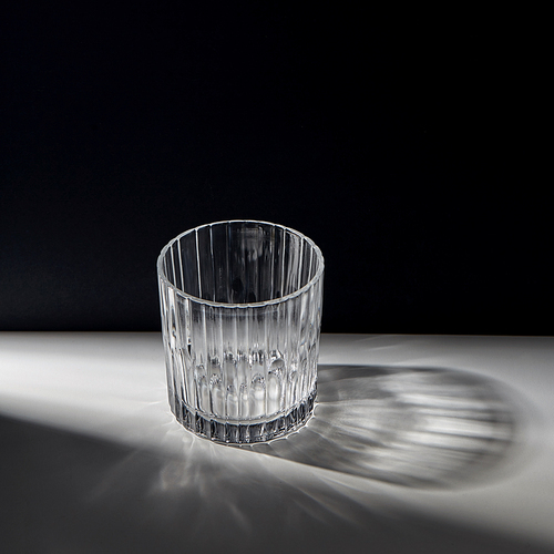 drink and glassware concept - empty faceted glass on table over black background