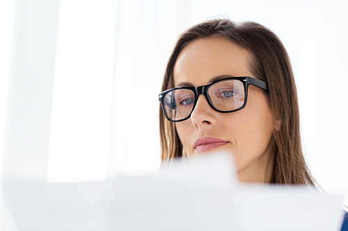 business, people and work concept - businesswoman in glasses reading documents at office