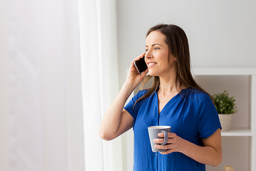 technology, communication and people concept - happy woman calling on smartphone and drinking coffee at office or home
