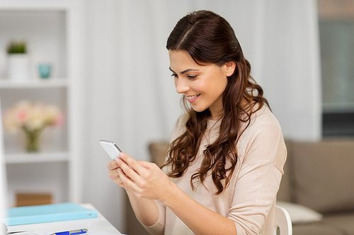 people, freelance and education concept - happy smiling woman messaging on smartphone at home