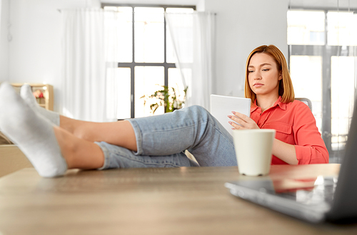 remote job, technology and people concept - young woman with notebook and laptop computer at home office resting feet on table