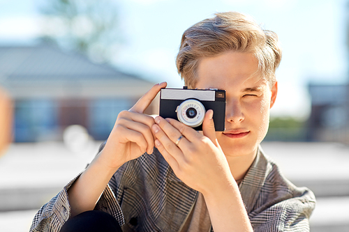 leisure, technology and people concept - young man or teenage boy with camera photographing in city