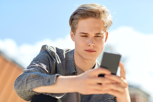 technology, communication and lifestyle concept - young man or teenage boy using smartphone outdoors