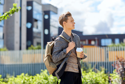 leisure and people concept - young man or teenage boy with backpack drinking takeaway coffee in city