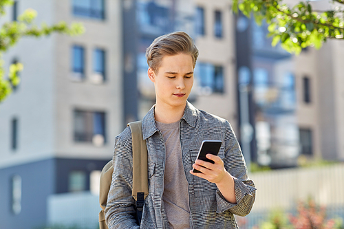 technology, leisure and people concept - young man or teenage student boy with smartphone and backpack on city street