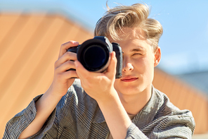 leisure, technology and people concept - young man or teenage boy with digital camera photographing outdoors