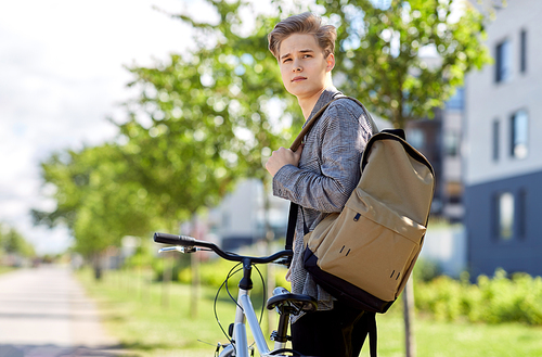 lifestyle, transport and people concept - young man or teenage boy with bicycle and backpack looking back on city street