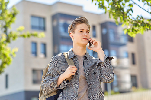technology, communication and lifestyle concept - young man or teenage student boy with backpack calling on smartphone on city street