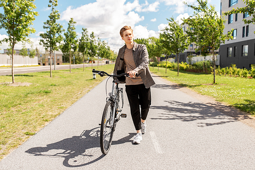 lifestyle, transport and people concept - young man or teenage boy with bicycle walking along city street