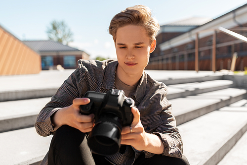 leisure, technology and people concept - young man or teenage boy with digital camera photographing in city
