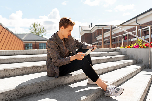 leisure, technology and people concept - young man or teenage boy with tablet pc in city