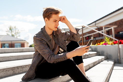 technology, communication and lifestyle concept - young man or teenage boy using smartphone in city