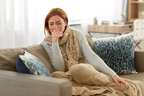 cold and health problem concept - sick woman in scarf and blanket coughing at home