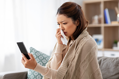 medicine, healthcare and technology concept - sick young asian woman with smartphone having video call or online consultation at home