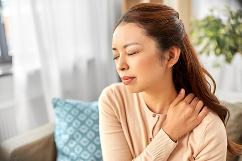 people, health and problem concept - tired asian woman suffering from ache in neck at home