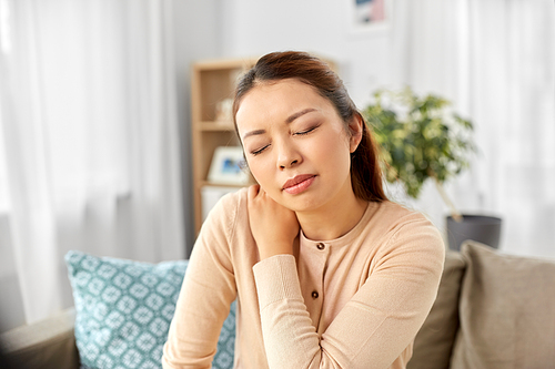 people, health and problem concept - tired asian woman suffering from ache in neck at home