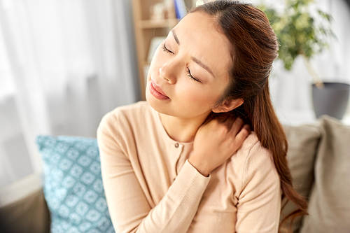 people, health and problem concept - tired asian woman suffering from ache in neck at home