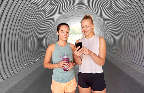 fitness, sport and healthy lifestyle concept - smiling young women or female friends with smartphone and flask