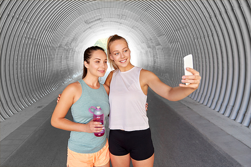 fitness, sport and healthy lifestyle concept - smiling young women or female friends taking selfie by smartphone outdoors