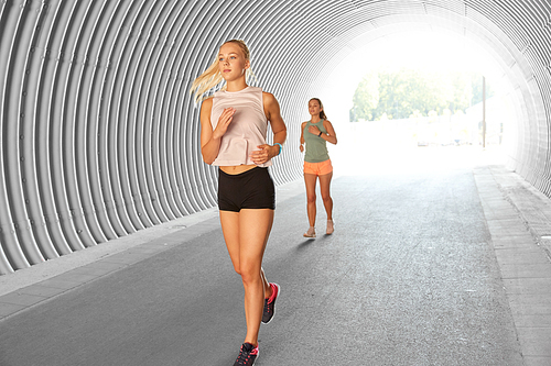 fitness, sport and healthy lifestyle concept - young women or female friends running outdoors