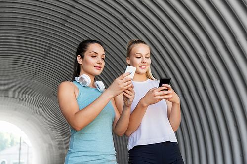 fitness, sport and healthy lifestyle concept - smiling young women or female friends with smartphones