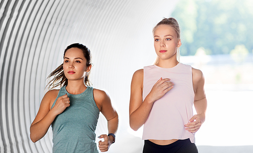 fitness, sport and healthy lifestyle concept - young women or female friends running outdoors