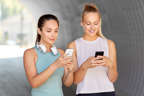 fitness, sport and healthy lifestyle concept - smiling young women or female friends with smartphones