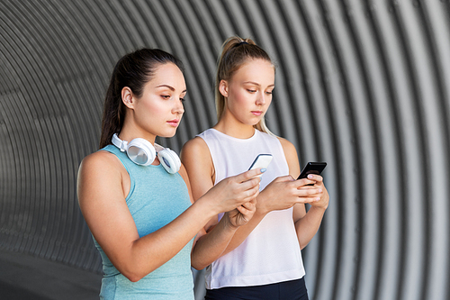 fitness, sport and healthy lifestyle concept - young women or female friends with smartphones