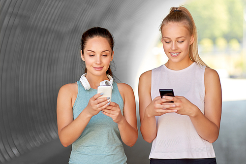 fitness, sport and healthy lifestyle concept - smiling young women or female friends with smartphones