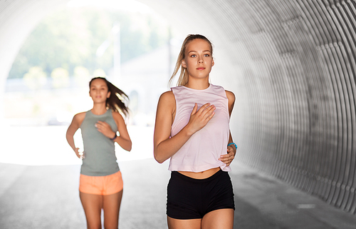 fitness, sport and healthy lifestyle concept - smiling young women or female friends running outdoors