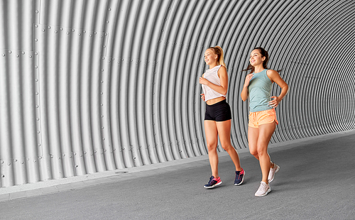 fitness, sport and healthy lifestyle concept - young women or female friends running outdoors